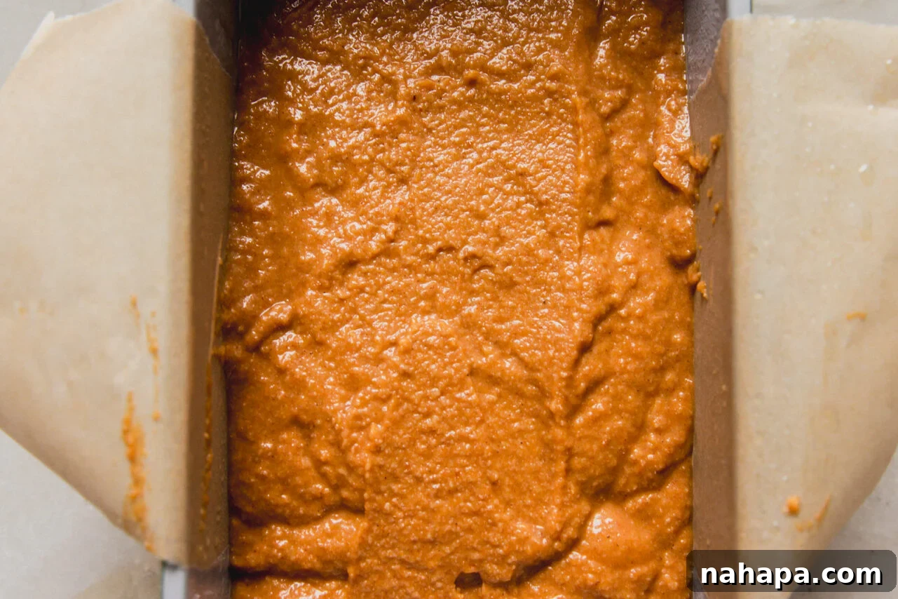 Spiced Almond Pumpkin Bread 7 Pumpkin bread batter poured into a parchment-lined loaf pan, ready for the oven.