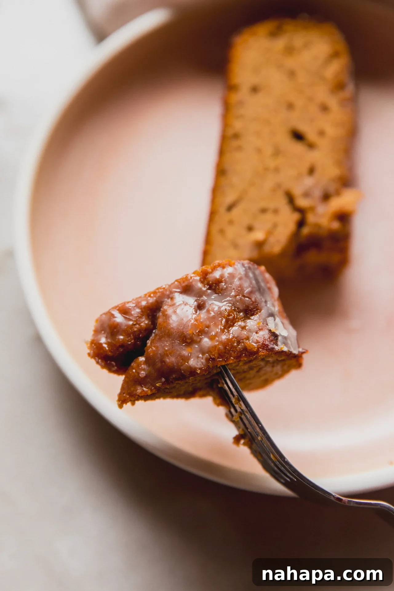Spiced Almond Pumpkin Bread 9 A fork taking a bite from a slice of moist almond flour pumpkin loaf, highlighting its appealing texture.