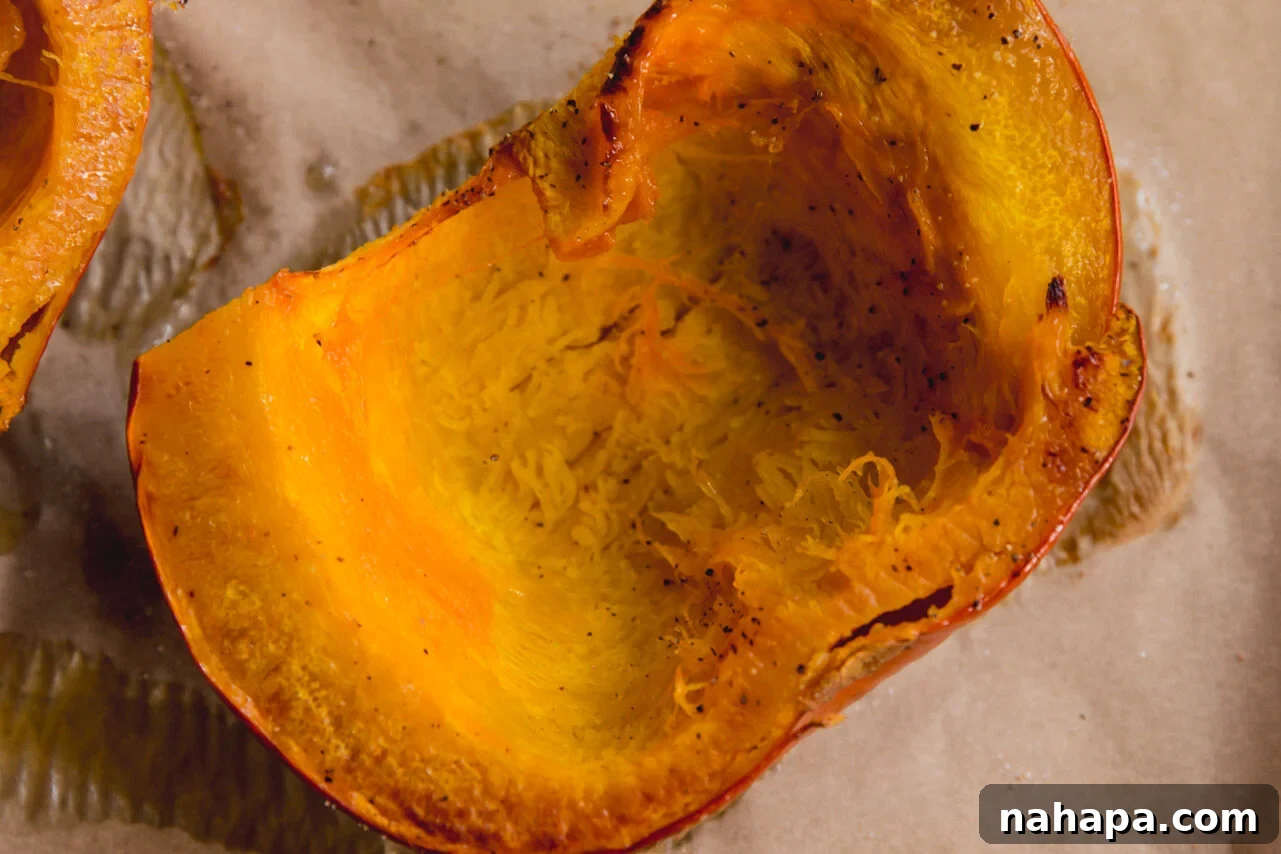 The roasted sugar pumpkin halves, cooked until tender, resting on a baking sheet after being removed from the oven.