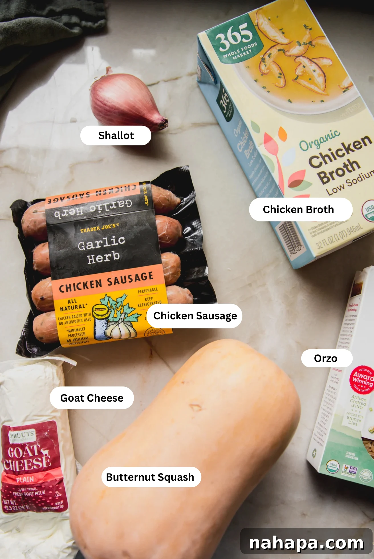 All the fresh ingredients for chicken sausage and orzo bake, laid out on a table.