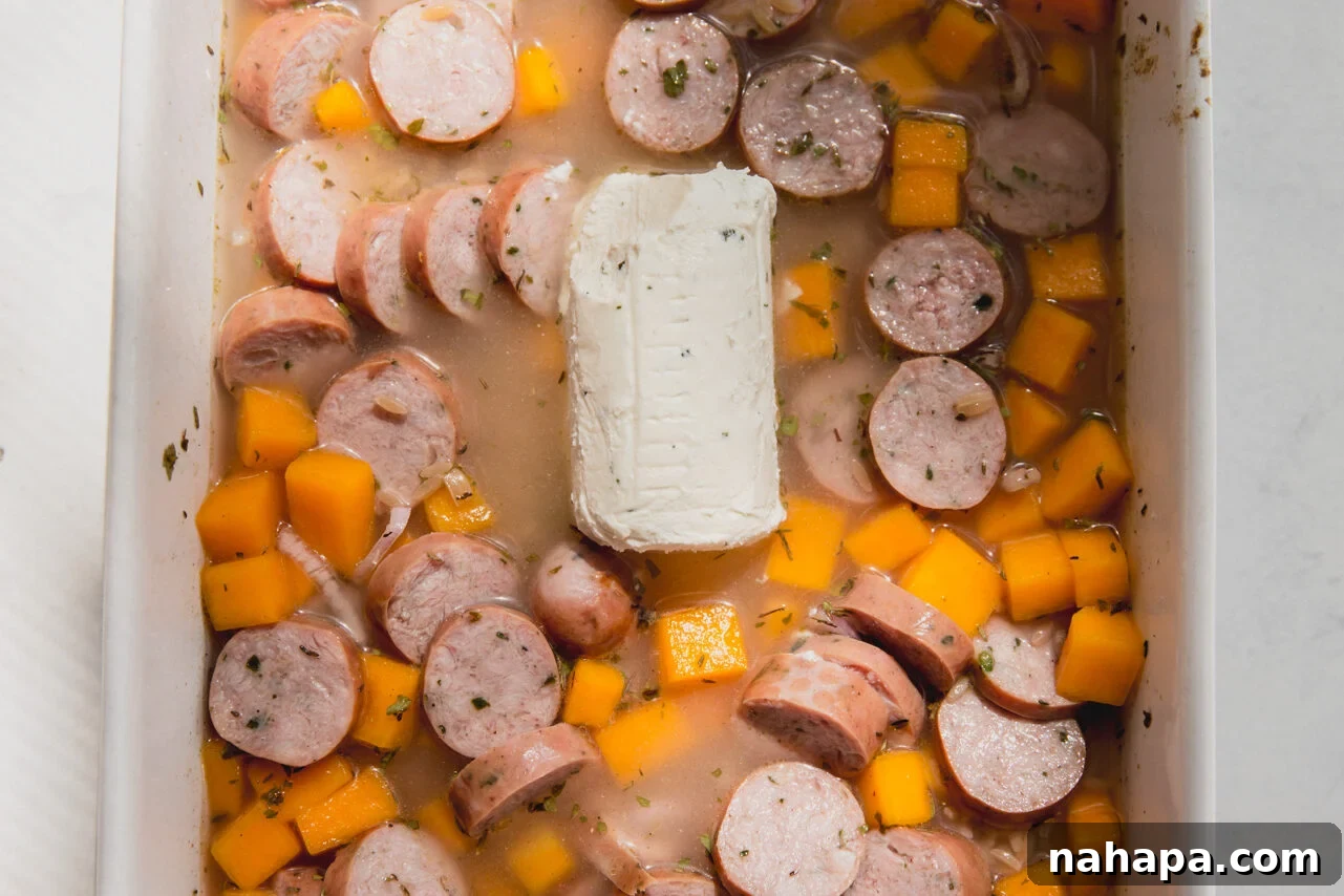 Chicken sausage, shallot, orzo, and broth added to the butternut squash in the baking dish.