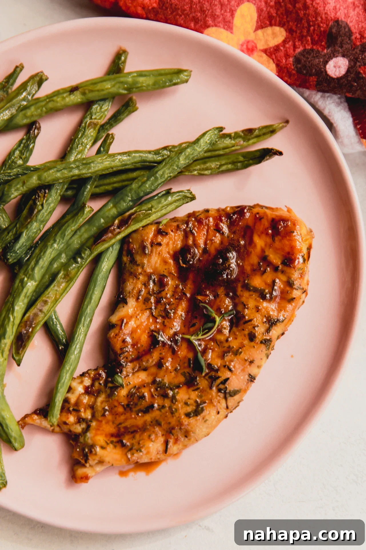 A plated dish of orange-glazed turkey cutlets served alongside vibrant green beans and a creamy side dish, garnished with fresh herbs.