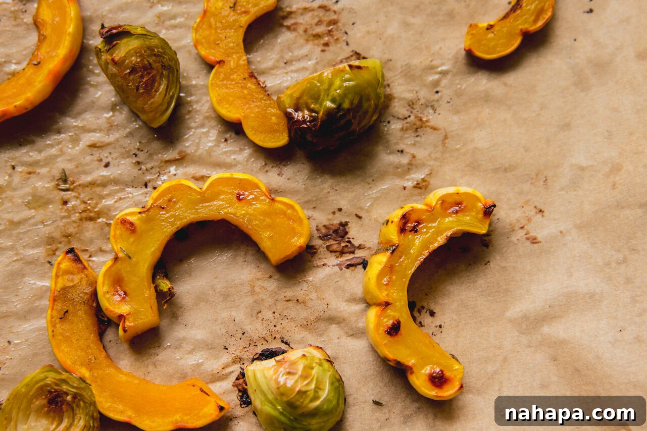 Golden Harvest Chicken & Squash Bowl 5 The roasted delicata squash and Brussels sprouts, golden brown and tender, on a baking sheet after being cooked to perfection.