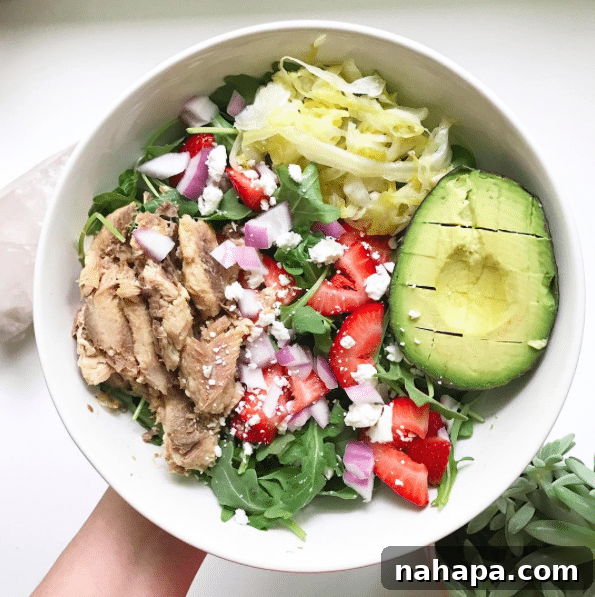 A bowl with a strawberry and avocado salad filling it.