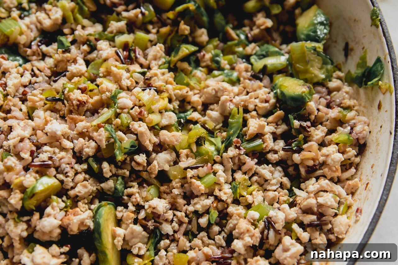 Cooked ground turkey, shredded Brussels sprouts, wild rice, and dried cranberries mixed together in a large pan.