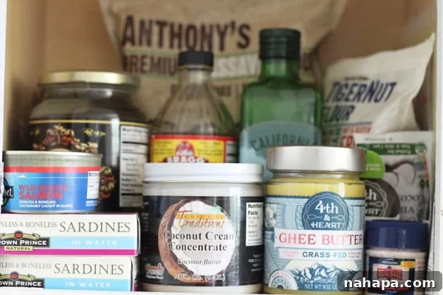 A shot of a pantry filled with coconut cream, ghee, sardines, olive oil, and apple cider vinegar among other things.