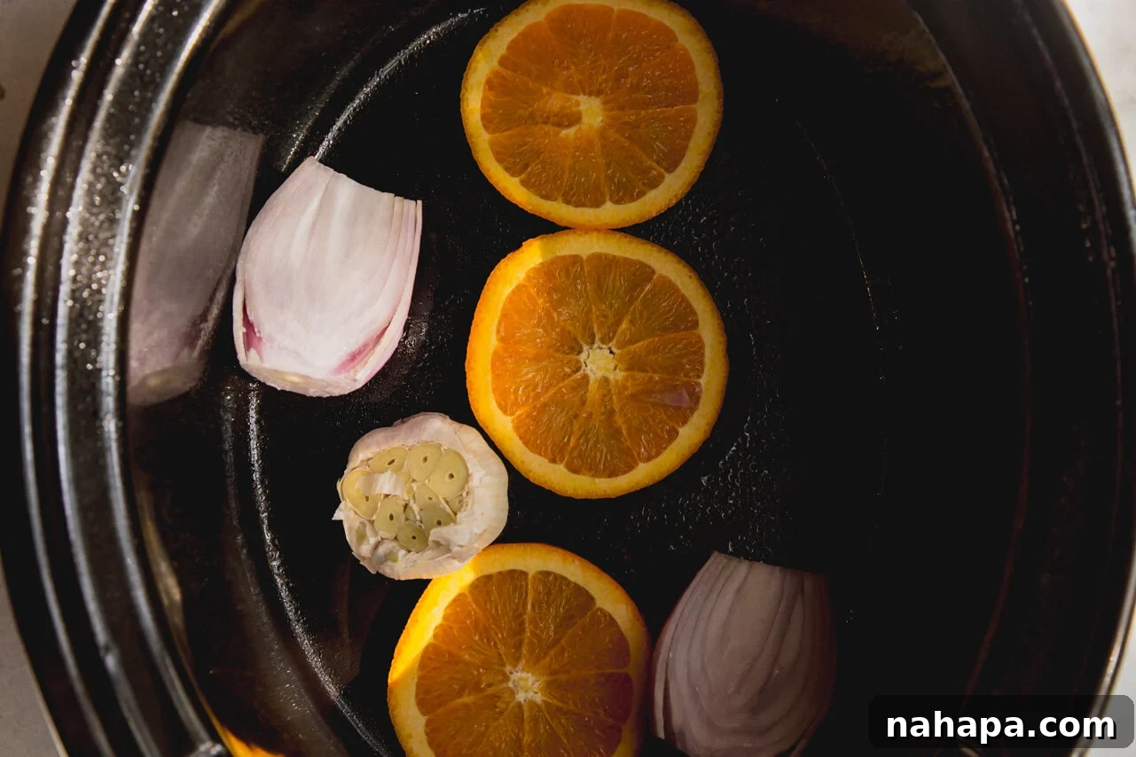Tender Maple Dijon Slow Cooker Turkey Breast 4 The slow cooker with orange slices, garlic, and shallot placed at the bottom, creating a fragrant bed for the turkey.
