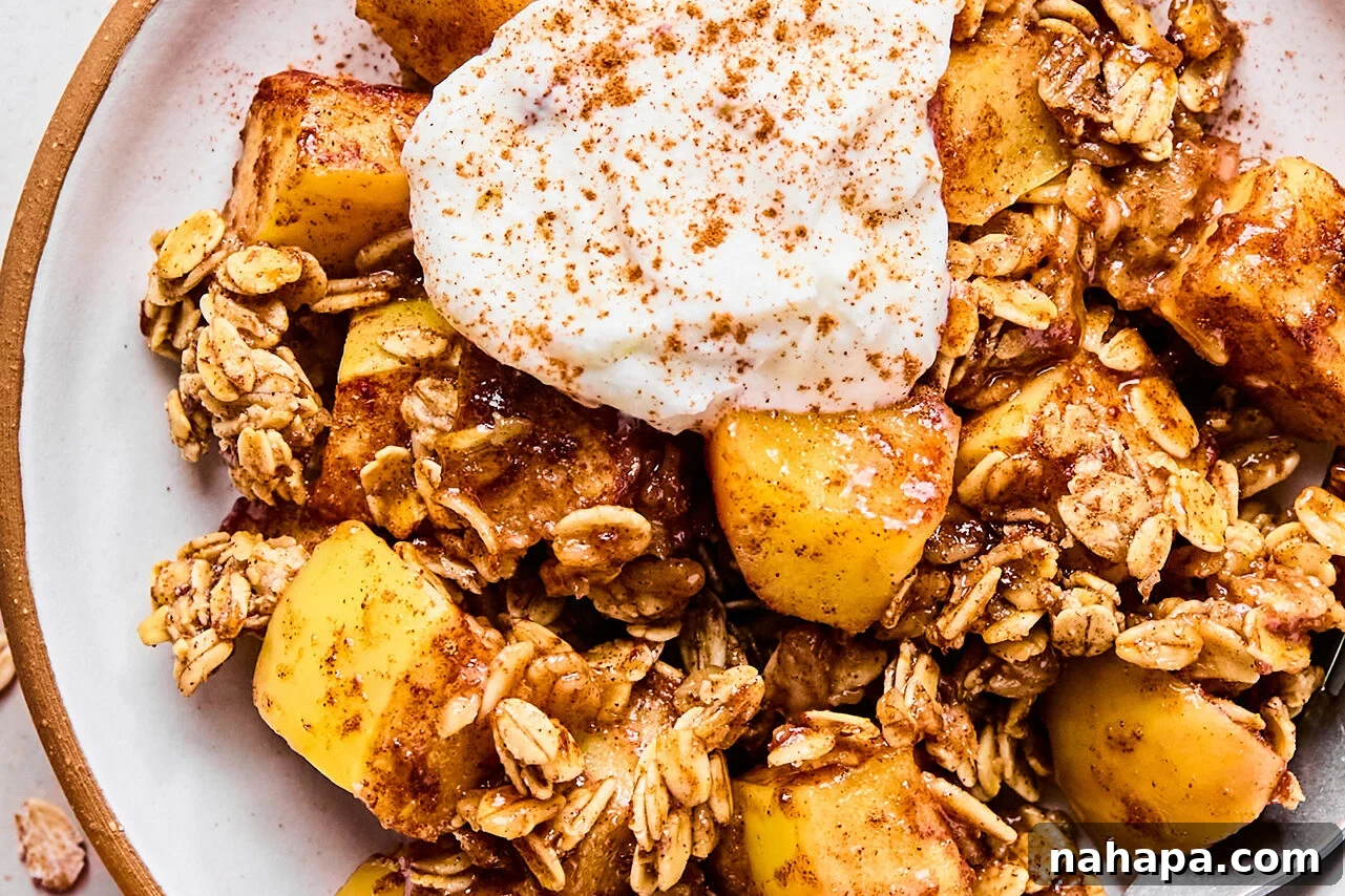 Protein-Packed Apple Crisp 8 A close-up of a serving of protein apple crisp on a plate, garnished with yogurt and a sprinkle of cinnamon.