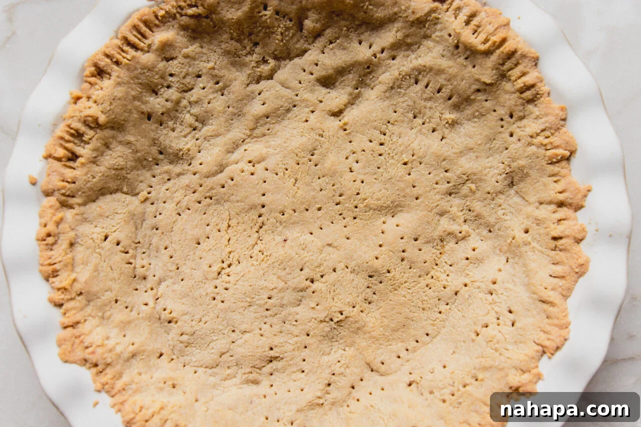 Decadent Gluten-Free Chocolate Chip Cookie Pie 4 A golden-brown, partially baked almond flour pie crust resting in a white pie pan, ready for the delicious filling.