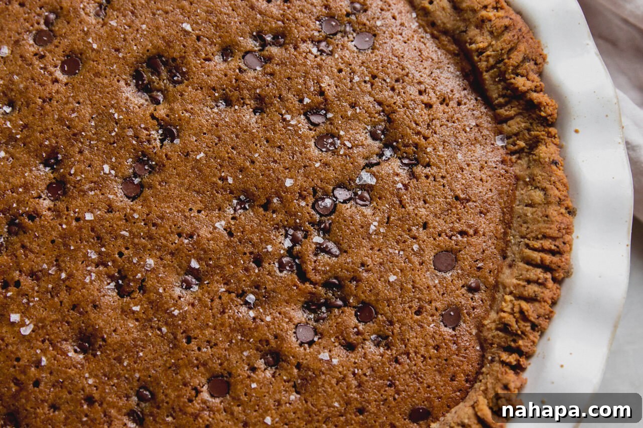 Decadent Gluten-Free Chocolate Chip Cookie Pie 7 A freshly baked gluten-free chocolate chip cookie pie, golden and inviting, presented in a large white pie pan, ready to be cooled and served.