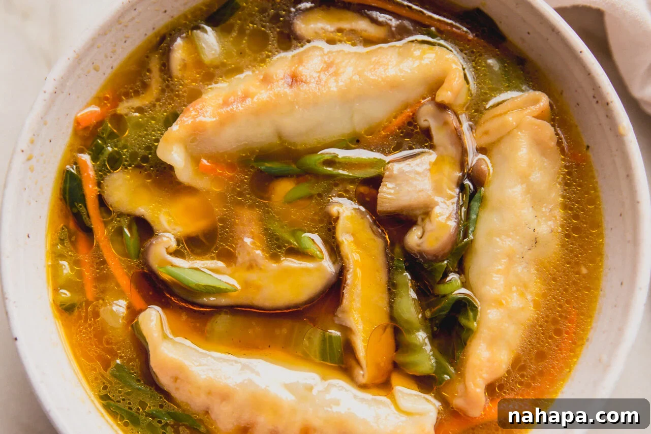 A beautifully composed bowl of gluten-free potsticker soup, garnished with fresh green onions, ready to be enjoyed.