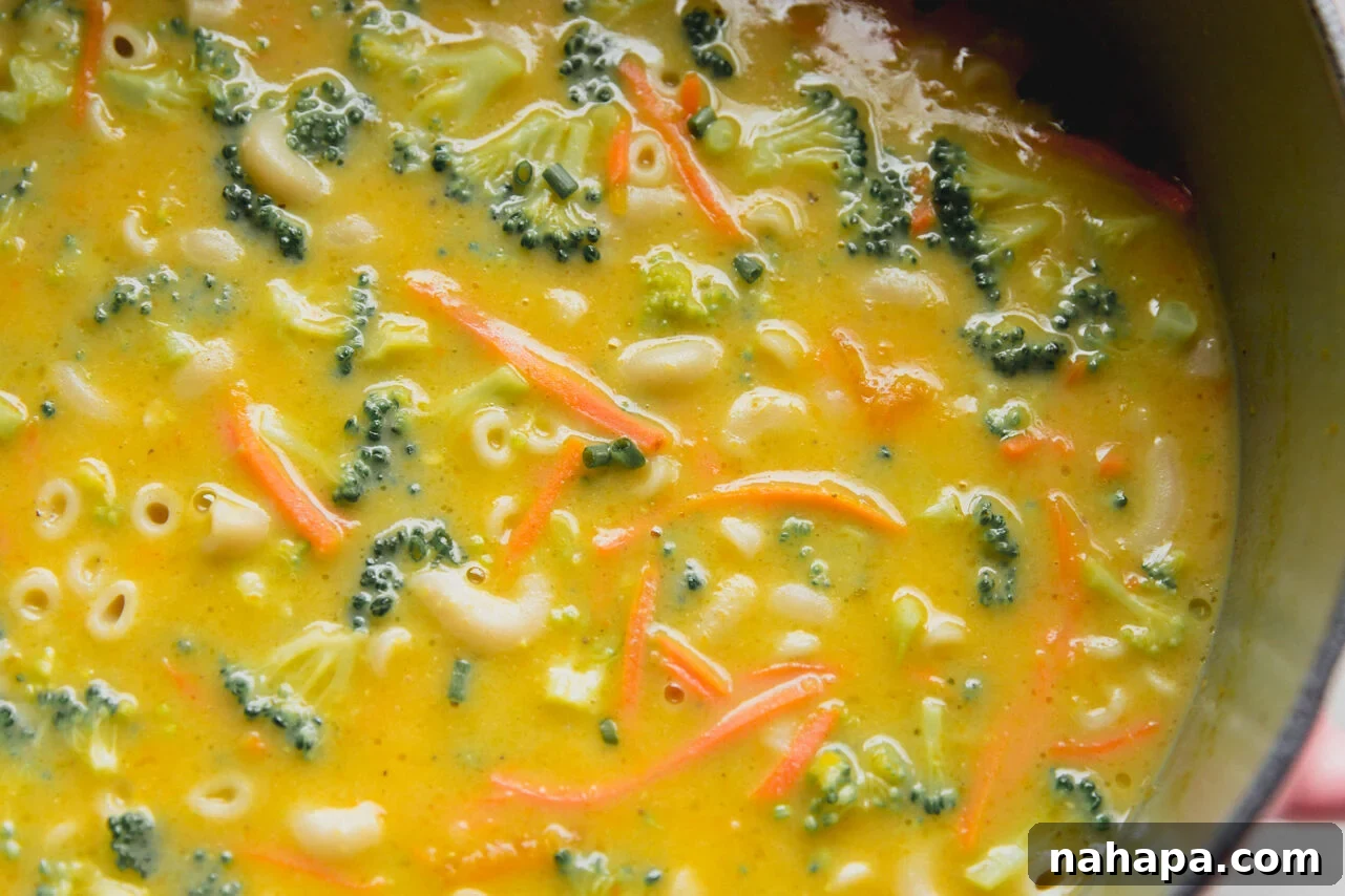 Finished dairy-free broccoli cheese noodle soup in a large pot, showing the creamy texture, broccoli, carrots, and gluten-free noodles.
