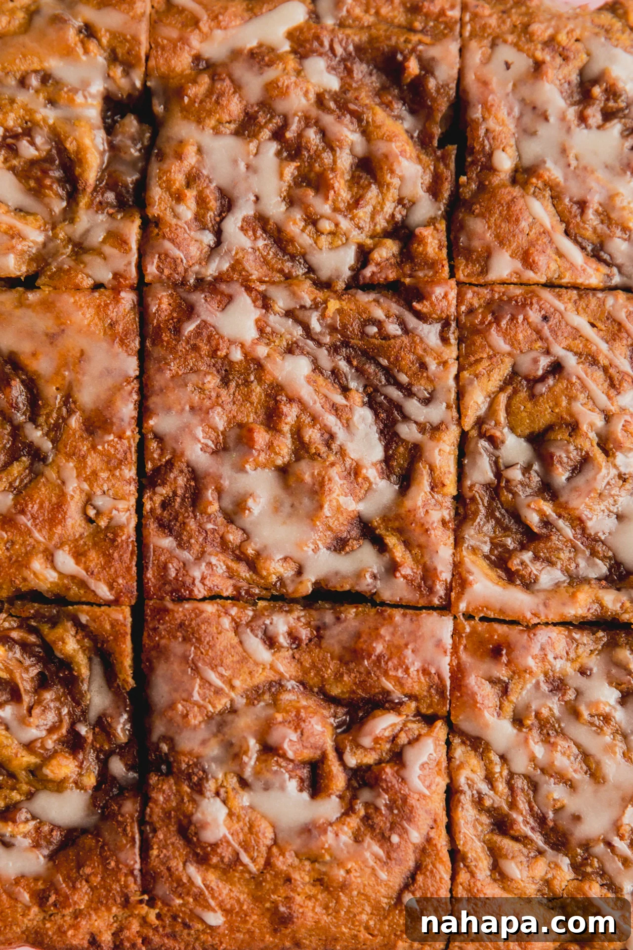 Gluten free cinnamon roll cake sliced into 9 slices and topped with a glaze icing.