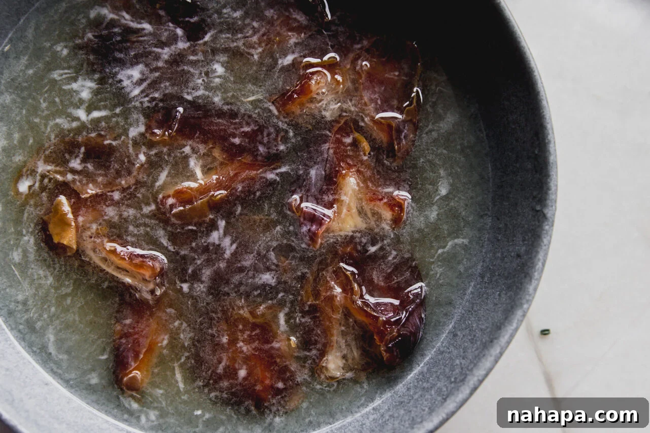 A grey bowl filled with dates soaking in hot water.