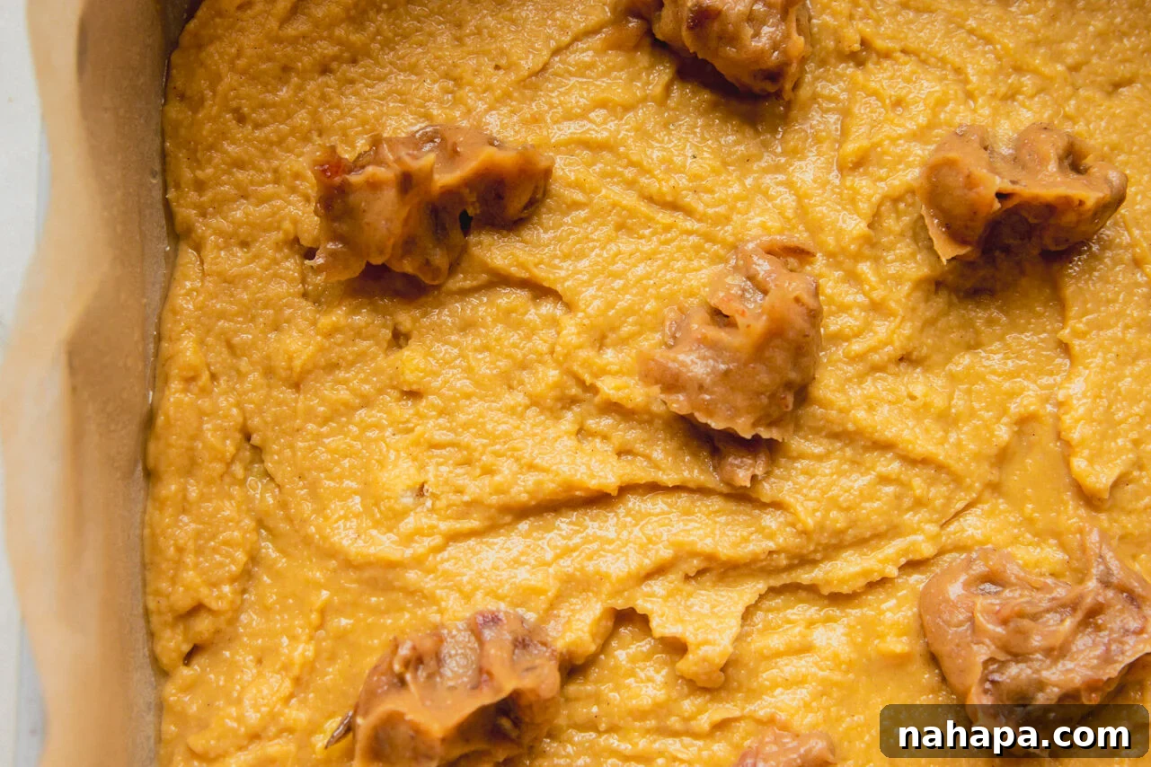 A baking dish with the cinnamon roll cake batter spread across it with small bits of the date mixture on top.