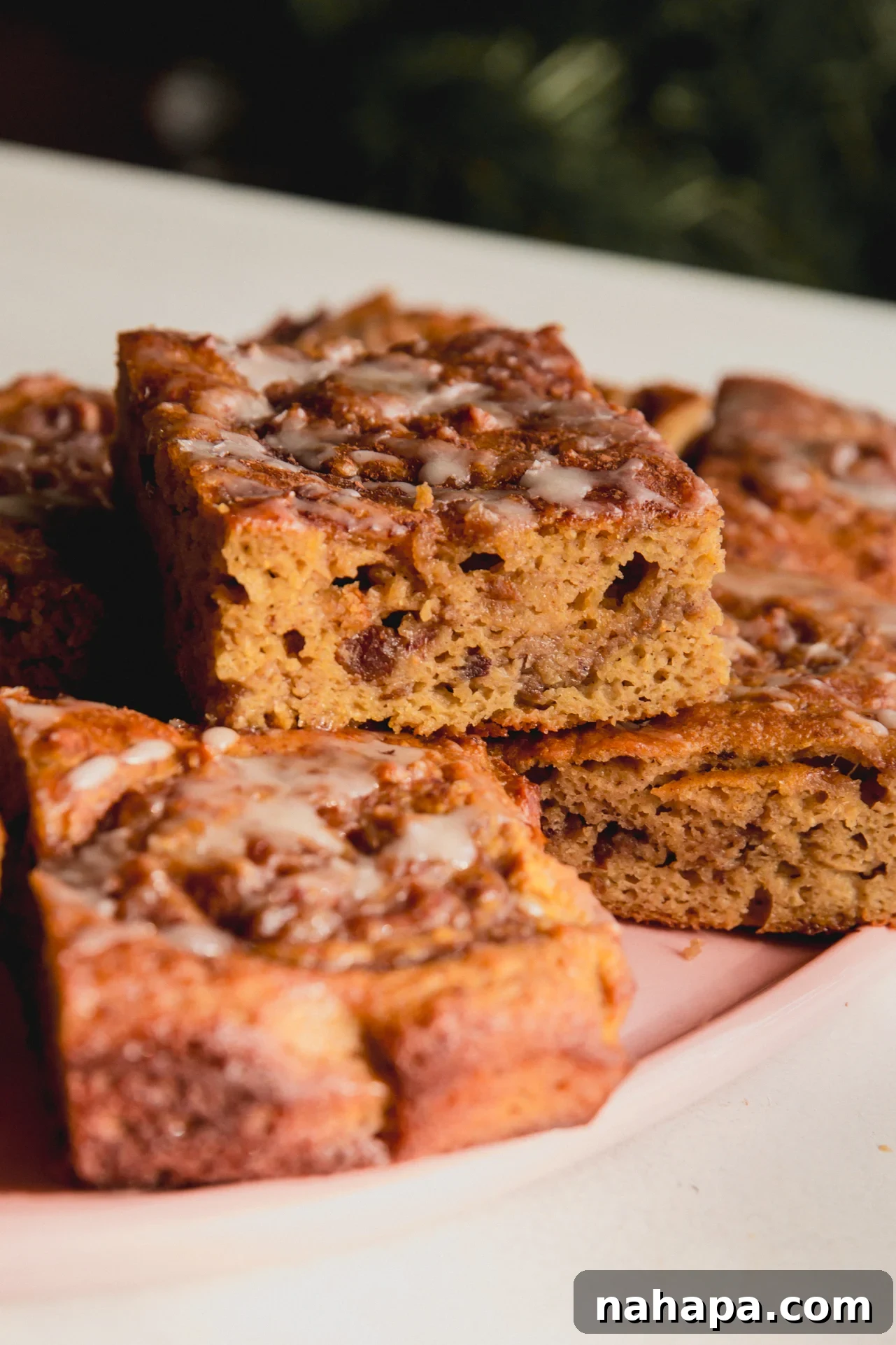 Pieces of cinnamon roll cake stacked on top of each other on a pink plate.
