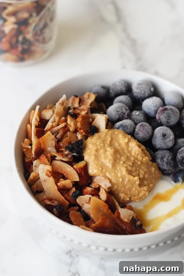 Grain Free Blueberry Coconut Granola (Paleo & AIP) served in a yogurt bowl with fresh berries.