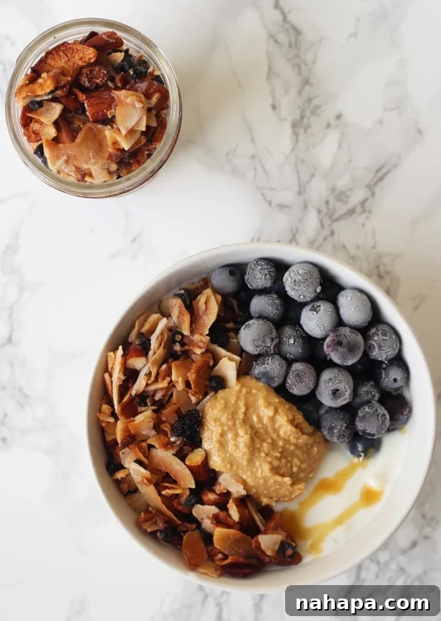 Grain Free Blueberry Coconut Granola (Paleo & AIP) in a vibrant yogurt bowl with fresh berries and mint.