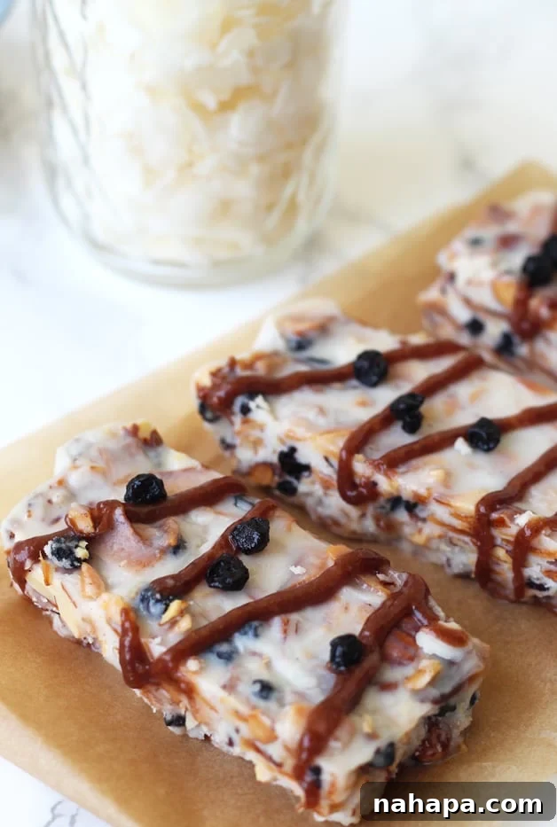 Three grain free granola bars sitting on a piece of parchment paper, ready to be enjoyed.