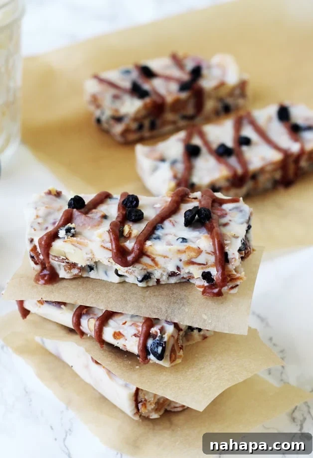 A few grain free granola bars on parchment paper and stacked with parchment paper between them, illustrating the finished product.