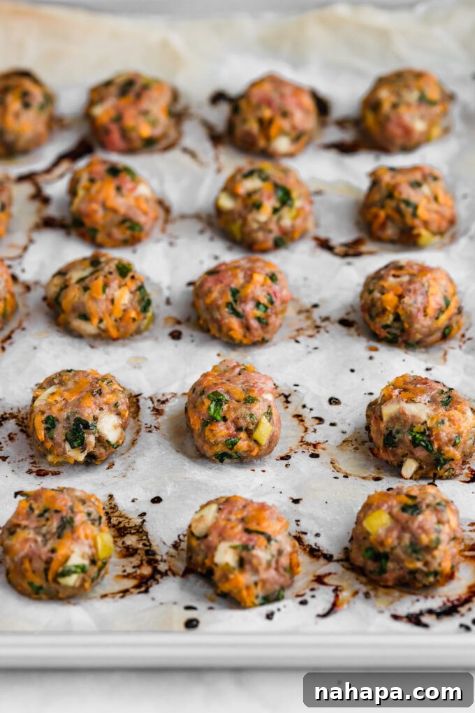 Golden-brown breakfast sausage chicken poppers fresh out of the oven on a parchment-lined baking sheet