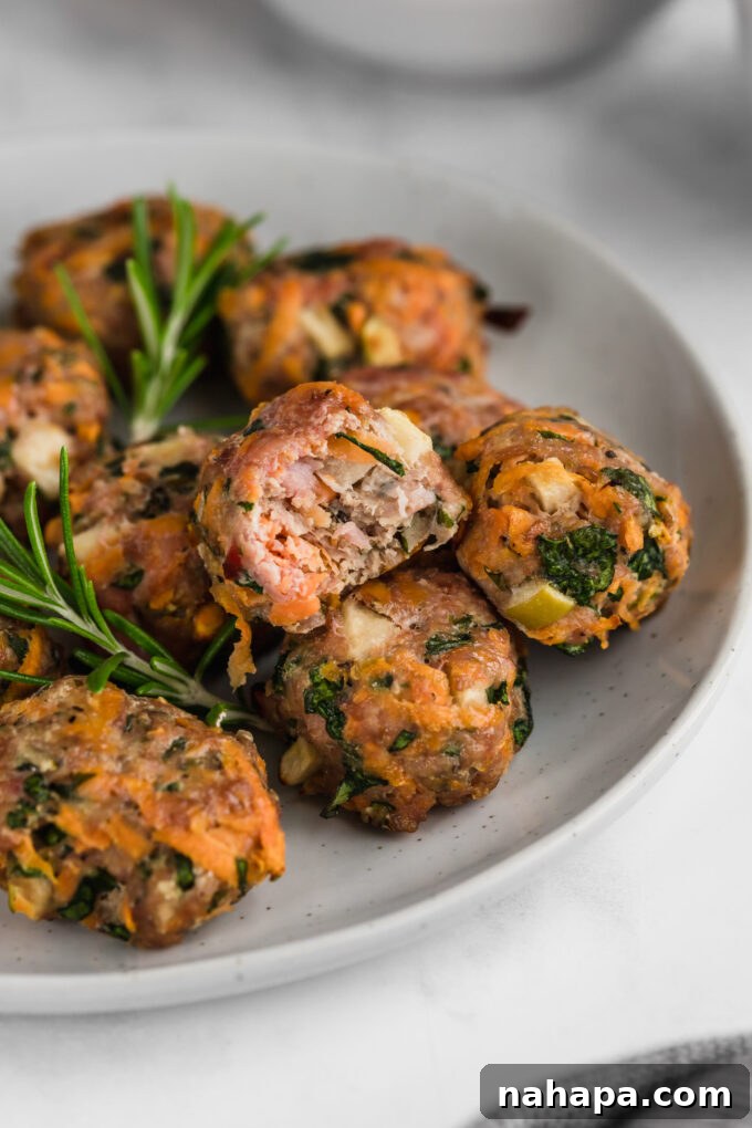 A vibrant plate of breakfast sausage chicken poppers, alongside fresh berries and a sprig of rosemary