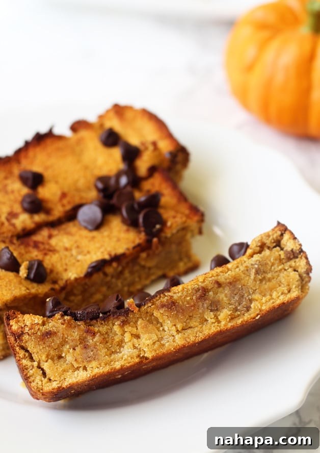 Paleo Chocolate Chip Pumpkin Bread, a golden-brown loaf with visible chocolate chips, sitting on a wooden cutting board with a knife and a few slices, highlighting its moist, tender texture suitable for AIP and gluten-free diets.