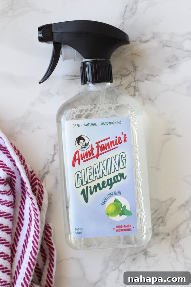 A shot of Aunt Fannie\'s Cleaning Vinegar in a spray bottle with a cleaning cloth next to it.