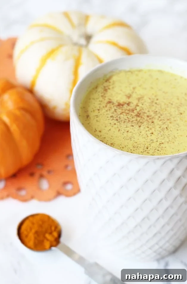 A hot beverage in a white mug sitting next to a few small squashes.