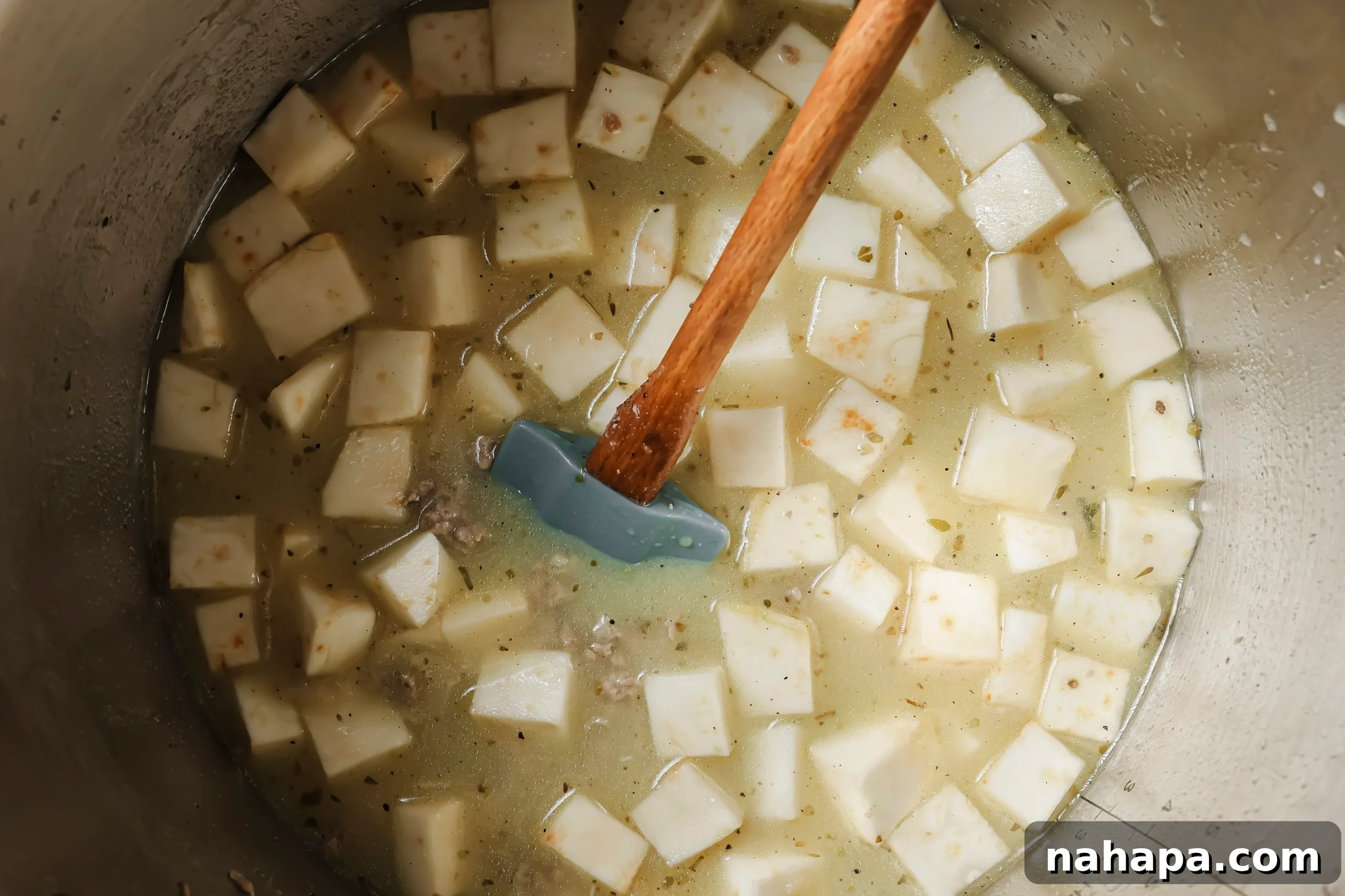 Chicken broth, coconut milk, diced sweet potato, and seasonings added to the Instant Pot with browned sausage.