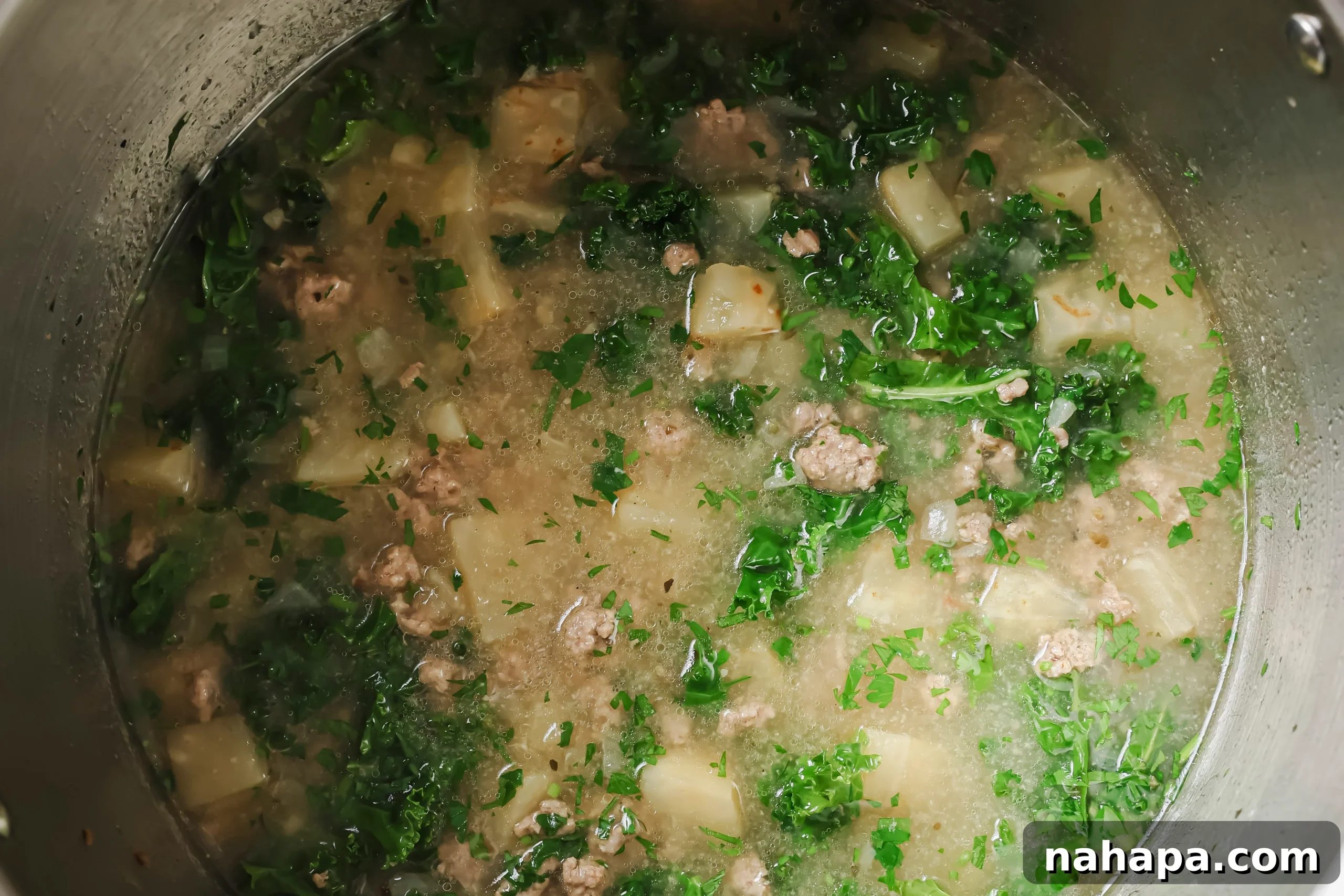 Fresh kale added to the hot Zuppa Toscana soup in the Instant Pot after pressure cooking.