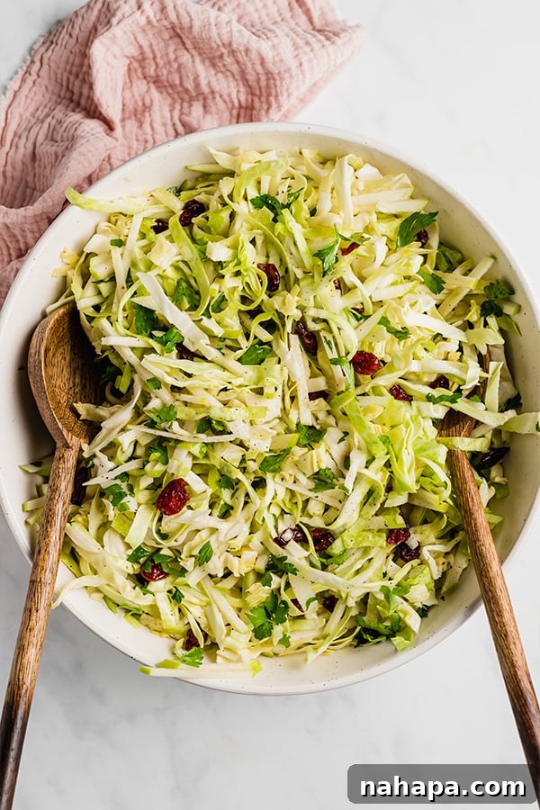 Thanksgiving Coleslaw in a rustic bowl with serving spoons, showcasing vibrant colors