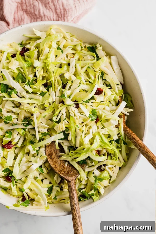 A close-up shot of the finished Thanksgiving coleslaw in a bowl with serving spoons