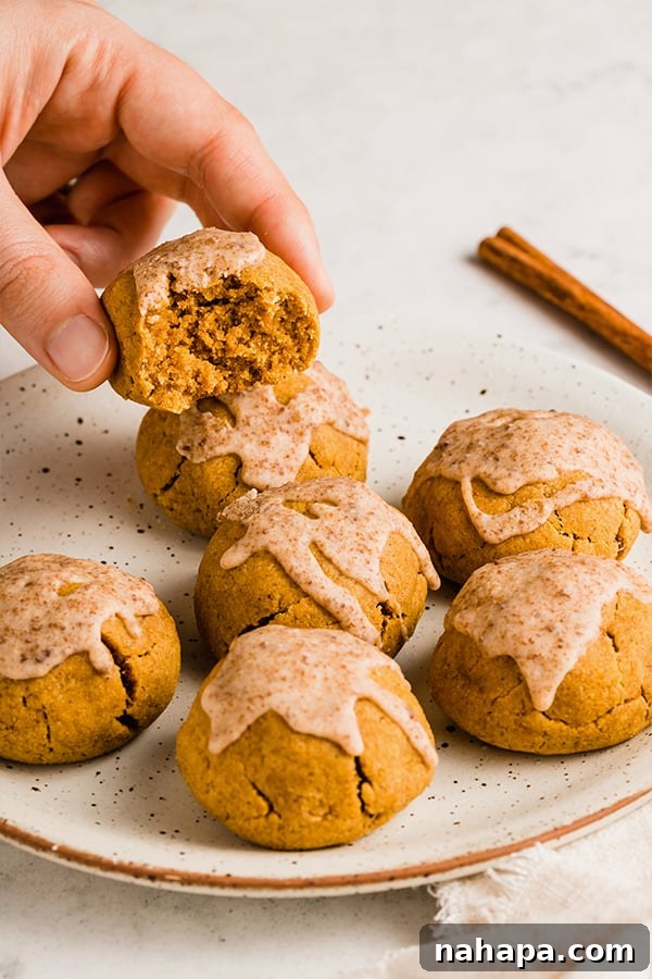 A hand reaching for a single pumpkin pie donut hole from a plate, showing its delicious texture.