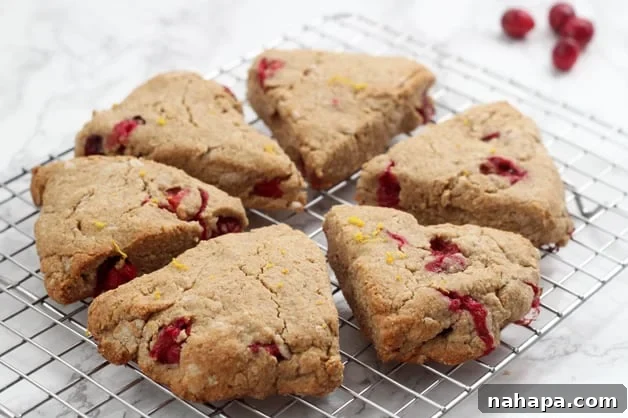 Two soft orange cranberry scones with a dusting of orange zest, ready to be enjoyed.