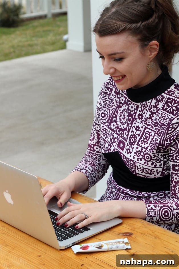 Michelle sitting in a purple and white dress typing at a computer.