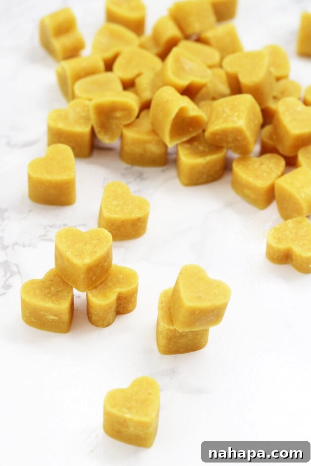 A pile of heart-shaped turmeric chewables, showcasing their vibrant golden color.