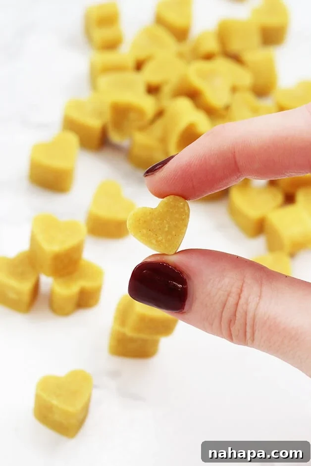 A stack of turmeric chewables with a hand holding one, highlighting their compact size and golden hue.