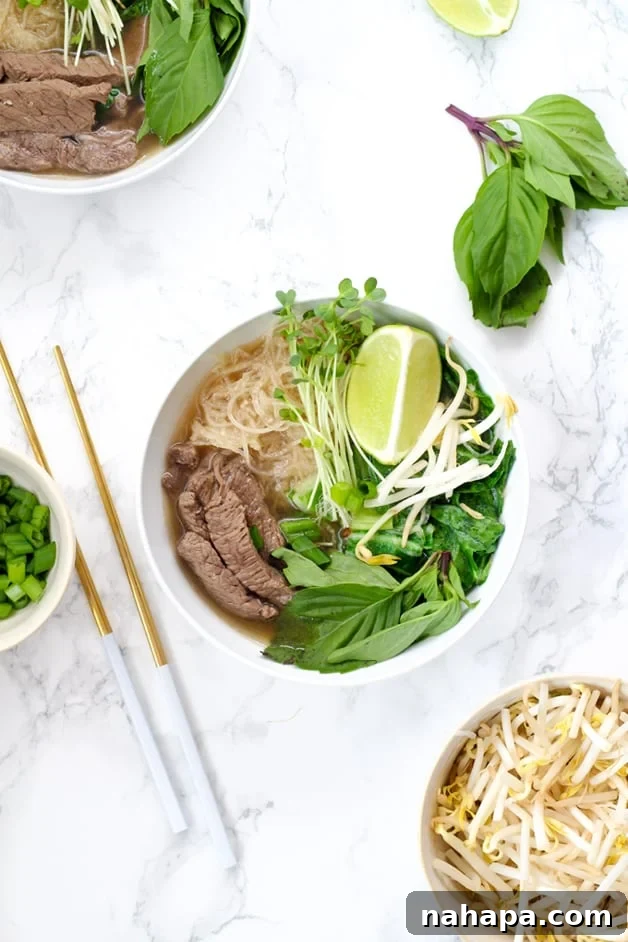 A vibrant bowl of Instant Pot Beef Pho, garnished with fresh herbs, tender beef, daikon radish noodles, lime wedges, and chopsticks resting beside it.