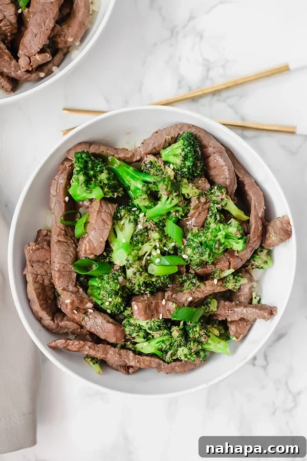 Wholesome Beef and Broccoli Whole30 Paleo AIP 2 A white bowl with beef and broccoli stir fry in it with chopsticks next to it.