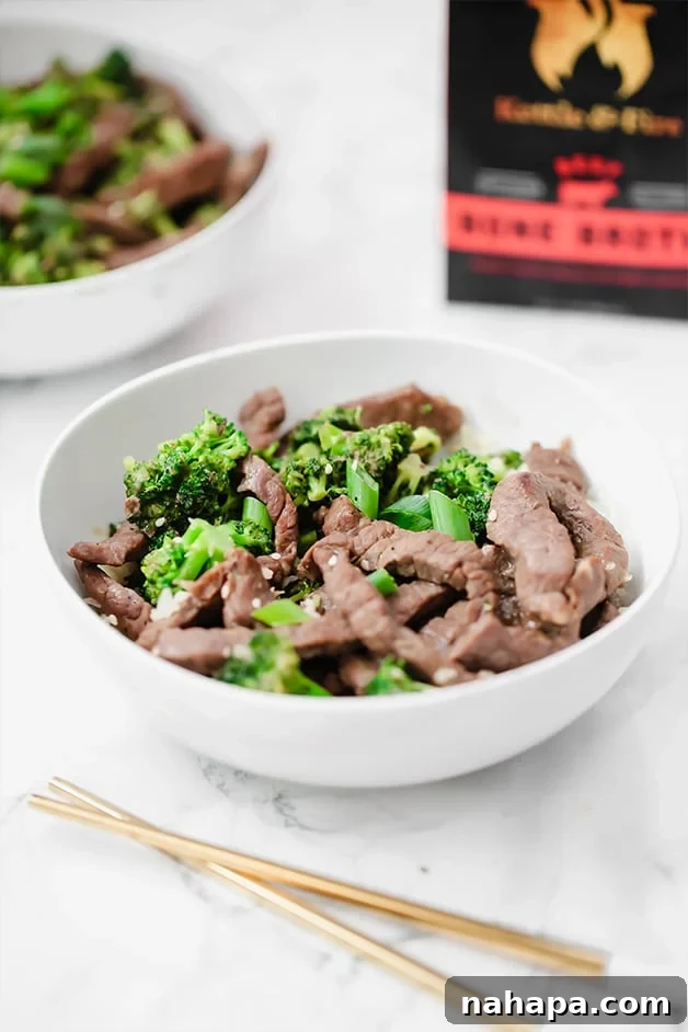 Wholesome Beef and Broccoli Whole30 Paleo AIP 4 A white bowl with beef and broccoli stir fry in it and chopsticks next to it.