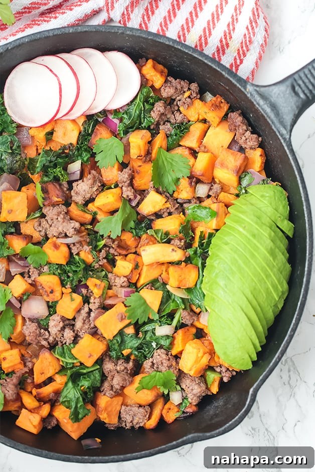 A black skillet filled with butternut squash, ground beef, avocado, and radish, creating a colorful breakfast or dinner.