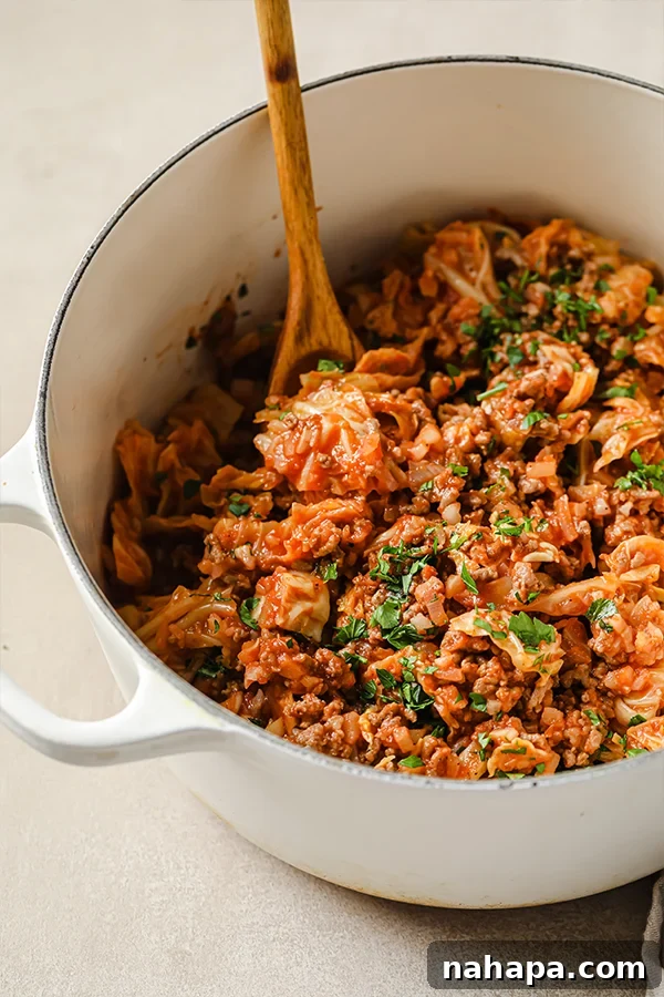 Unstuffed cabbage roll in a white pot with a wooden spoon.