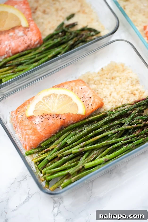 A glass meal prep container filled with roasted asparagus, salmon, and cauliflower rice.