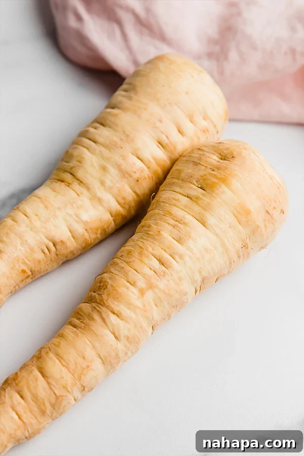 Several large, fresh raw parsnips displayed on a surface, highlighting their smooth texture and readiness for preparation.