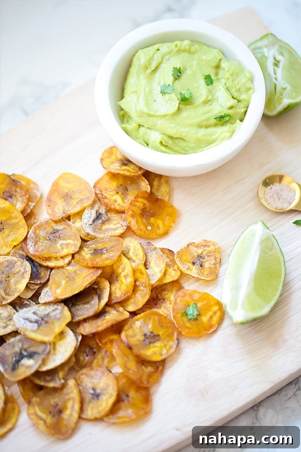 Close-up of baked plantain chips scattered on a white surface, highlighting their golden brown color and crisp texture.