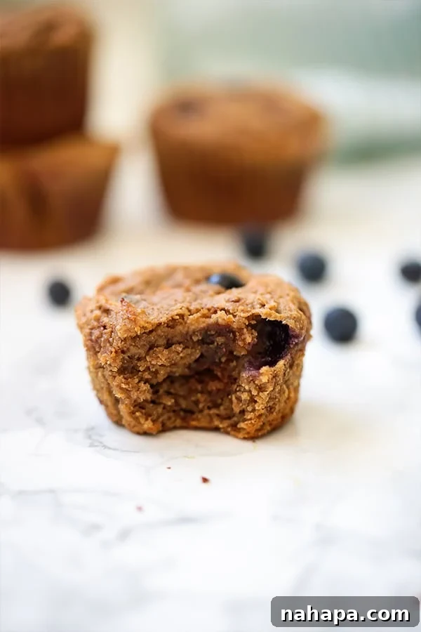 Wholesome Paleo AIP Egg-Free Blueberry Banana Muffins 3 A blueberry banana muffin with a bite taken out of it next to some loose blueberries.