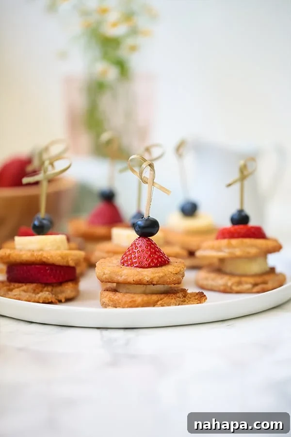 Delicious Paleo Vegan Gluten Free Pancake Skewers 3 A white plate with mini pancakes on skewers with fresh fruit.