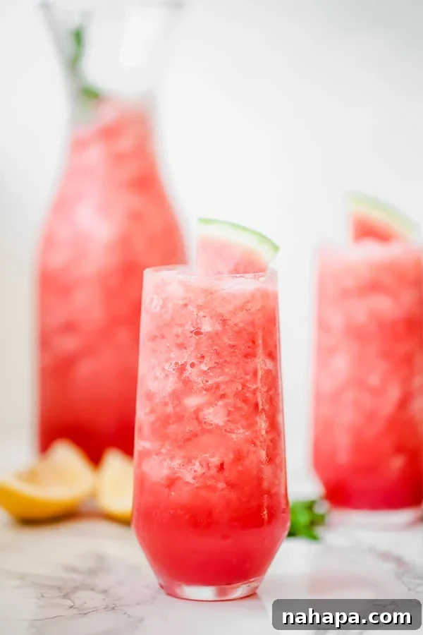 Two glasses filled with watermelon mocktail and a carafe of watermelon mocktail behind it.