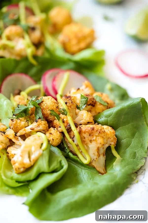A close up of a bang bang cauliflower taco with crisp lettuce and a sprinkle of fresh radish on a rustic wooden surface, highlighting the vibrant colors and appealing texture of the dish.